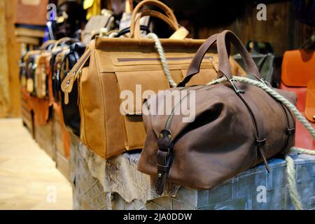 Herren Accessoires mit braunen Ledertaschen auf Holztisch über Wandhintergrund. Stockfoto