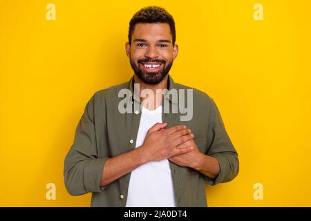 Foto von verträumt gut aussehend Kerl gekleidet grünen Hemd Arme Brust lächelnd isoliert gelben Hintergrund Stockfoto