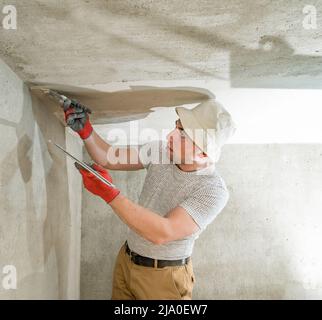 Kalkputz zum Nivellieren der Wände, der Meister führt Reparaturen im Raum durch, ebnen die Wände mit Betonmörtel. Stockfoto