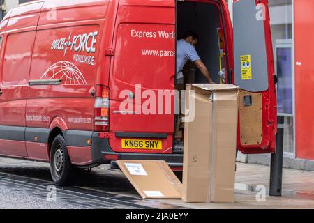 Voll beladener Express Parcel Force Delivery man; Royal Mail Vehicle mit zerquetschten zerbrechlichen Paketen, 'This Way Up' beschädigte Boxen, die geliefert werden Stockfoto