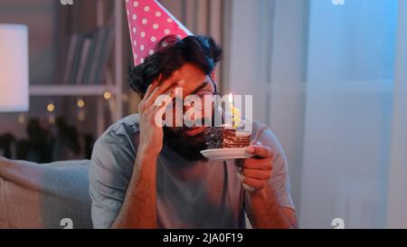 Porträt Araber traurig verärgert einsamer indischer bärtiger Mann feiert Geburtstag allein ohne Freunde fühle Traurigkeit Kopfschmerzen Scheitern männlich in festlichem rosa Hut Stockfoto