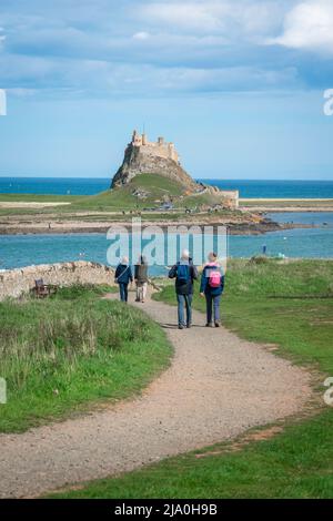 Reifes Paar beim Gehen, Rückansicht bei sonnigem Wetter eines reifen Paares auf Holy Island (Lindisfarne), Northumberland, England, Großbritannien Stockfoto