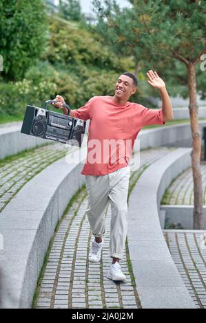 Typ mit Plattenspieler, der seine Hand beim Gruß hebt Stockfoto