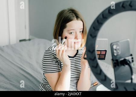 Kaukasische Teenager-Bloggerin, die ein Tutorial-Video für ihren Beauty-Blog mit dem Smartphone zu Hause aufzeichnet Stockfoto