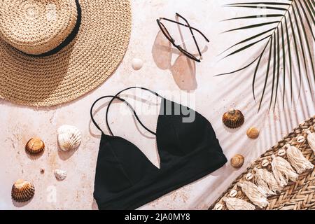 Urlaubsreise flach lag mit Bikini, Strohhut, Meer-Souvenirs auf beigem Stein Hintergrund mit harten Schatten, Draufsicht Stockfoto