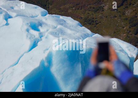 Ein Tourist, der Fotos vom Perito-Moreno-Gletscher mit einem Smartphone macht, Los Glaciares-Nationalpark, Argentinien. Stockfoto