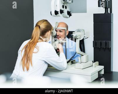 Augenuntersuchung durch Augenoptikerin mit Hilfe der Spaltlampe Stockfoto