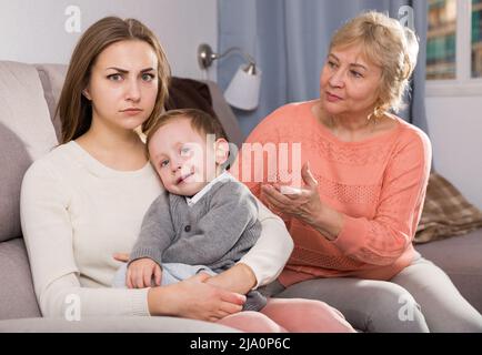 Zwei Erwachsene Frauen haben Meinungsverschiedenheiten mit dem erwachenden Kind Stockfoto