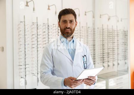 Augenarzt mit Brillen mit digitalem Tablet während der Arbeit im optischen Geschäft Stockfoto