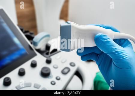 Ultraschallsonde in der Hand des Arztes, Nahaufnahme in der Nähe des Ultraschallgeräts in der Klinik. Sonographie Stockfoto