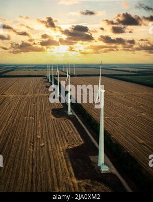 Windturbinenpark bei Sonnenuntergang mit dramatischem Himmel. Erzeugung alernativer Energie. Konzept für erneuerbare Energien. Stockfoto