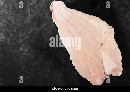 Pangasius gefrorenes Filet. Rohes Filet aus weißem Fischwels. Pangasius mit Gewürzen. Schwarzer Hintergrund. Draufsicht. Stockfoto