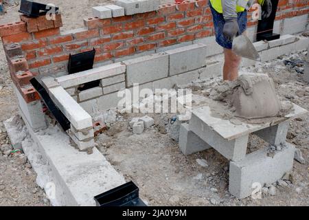 Maurerwerk, das Ziegelsteine auf Mörtel auf dem neuen Wohnhausbau verlegt Stockfoto