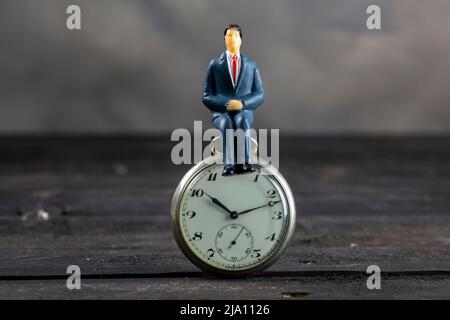 Geschäftsmann sitzt auf einer Uhr. Zeitkonzept. Stockfoto