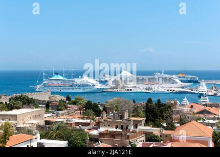 Ein Blick über Rhodos-Stadt, Rhodos in Richtung des alten Hafens und der Mandraki Marina zeigt zwei große Kreuzfahrtschiffe, die während des Besuchs der berühmten Stadt vor Anker liegen Stockfoto