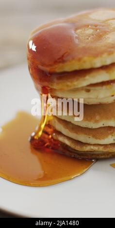 Vertikales Bild von Ahornsirup, der auf einen Stapel amerikanischer Pfannkuchen gegossen wird Stockfoto