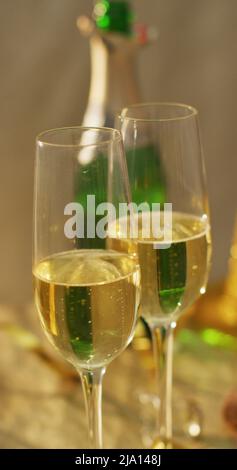Vertikales Bild von zwei Gläsern Champagner und offener Champagnerflasche auf dem Tisch Stockfoto