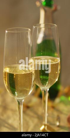 Vertikales Bild von zwei Gläsern Champagner und offener Champagnerflasche auf dem Tisch Stockfoto