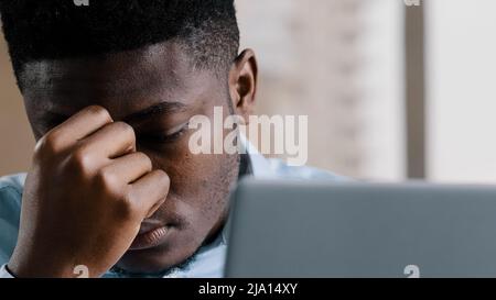 Nahaufnahme erschöpft jungen tausendjährigen afrikanischen Geschäftsmann überarbeitet Mann massieren trocken reizbare Augen Gefühl Augenbelastung Beschwerden Kopfschmerzen Müdigkeit Stockfoto