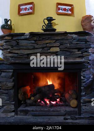Traditioneller Steinkamin mit brennenden Holzstämmen Stockfoto