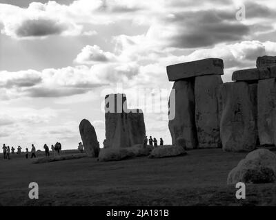 Teil von Stonehenge mit den Silhouetten von Touristen im Hintergrund, in Schwarz und Weiß, was der Szene ein unheilvolles Gefühl gibt Stockfoto