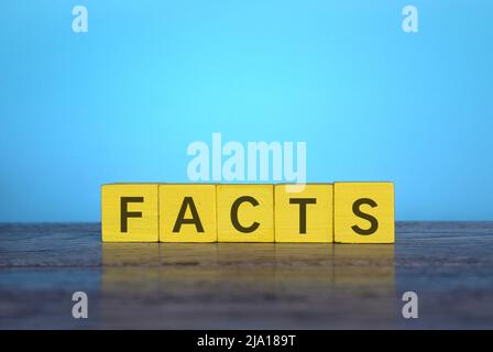 Holzwürfel auf dem Tisch mit Text FAKTEN. Blauer Hintergrund Stockfoto