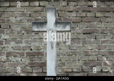 Wien, Österreich. Der Wiener Zentralfriedhof. Steinkreuz vor einer Ziegelmauer Stockfoto