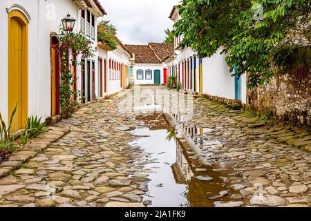 Gepflasterte Straße mit bunten Kolonialhäusern und Reflexionen in den Pfützen in der historischen Stadt Paraty, Rio de Janeiro, Brasilien Stockfoto