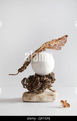 Badebombe auf Stein mit trockenem Blatt auf weißem Hintergrund. Stillleben für Resort Spa oder Salon. Entspannen, Wellness-Konzept. Balance Komposition. Stockfoto