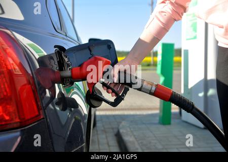Tanken Sie das Auto auf. Eine Frau an einer Tankstelle betankt das Auto an einem sonnigen Sommertag mit Kraftstoff. Stockfoto