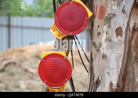 Rote Reflektoren sind an einem Holzbalken an der Seite einer Baustelle befestigt, die ein Sicherheitselement ist Stockfoto