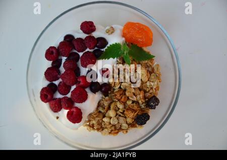 Gesunde Frühstückschale mit hausgemachtem Müsli. Richtige Ernährung Schüssel Hafergranola mit Joghurt, frischen Himbeeren, Heidelbeeren, Erdbeeren Stockfoto