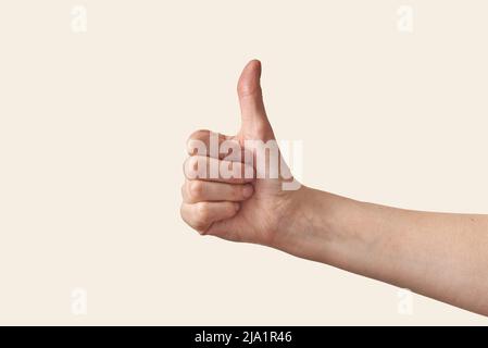 Männliche Hand mit Daumen nach oben auf cremefarbenem Hintergrund. Stockfoto