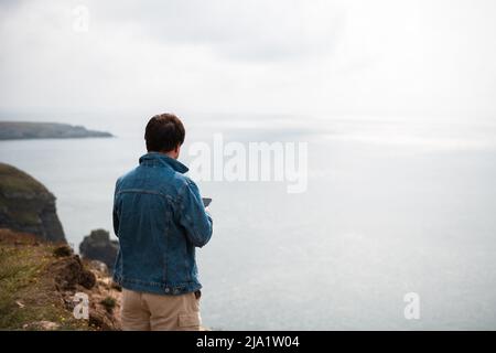 Der Mensch steht am Rand der Klippe auf dem irischen Meer Stockfoto