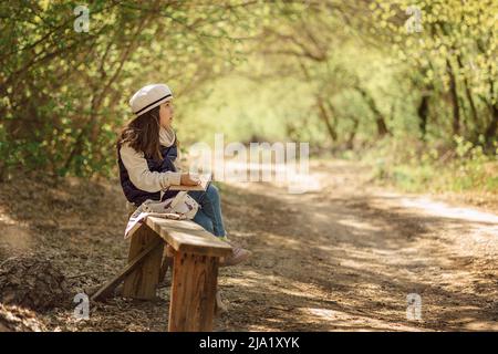 Kleines Mädchen malt im Frühling im Freien blühenden Märchenpark. Kinderzeichnungen. Kreatives Kind. Freude an der Kindheit. Hochwertige Fotos Stockfoto