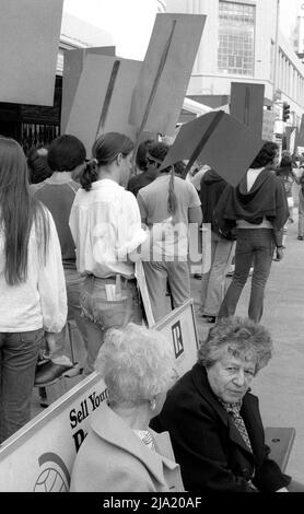 Zwei ältere Damen warten an einer Bushaltestelle, während junge Demonstranten mit Plakaten am Wilshire Boulevard in Los Angeles, CA, vorbeilaufen. Stockfoto