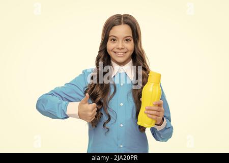 Glückliches Kind Daumen hoch Hand Geste hält gelbe Kunststoff-Trinkflasche, Genehmigung Stockfoto