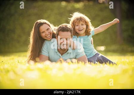 Freundschaft. Vater Mutter und Kind auf grünem Parkgras. Freundliche Familie haben Spaß im Sommer Stockfoto