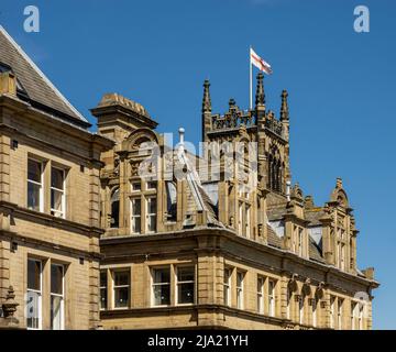 Kunstvolle obere Etage der denkmalgeschützten Kirkgate-Gebäude der Klasse II in Huddersfield mit dem Kirkgate-Kirchturm dahinter. West Yorkshire Stockfoto