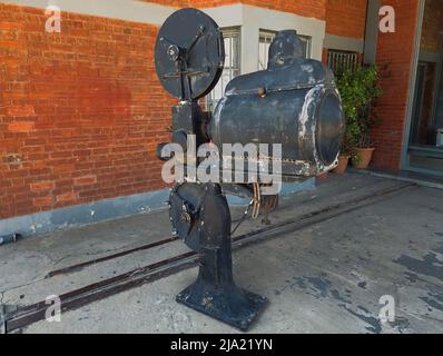Ein alter alter alter Vintage-Filmprojektor aus dem Jahr 35mm, der vor einem ehemaligen Lagerhaus in Thessaloniki, Griechenland, ausgestellt wird. Stockfoto
