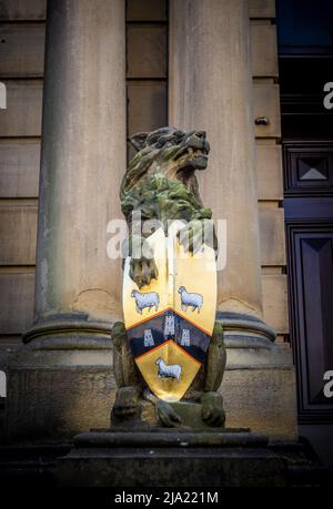 Steinlöwenstatue mit einem Schild, eines von einem Paar am Eingang zum Rathaus von Huddersfield. Huddersfield. West Yorkshire. Stockfoto
