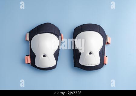 Draufsicht des Rollschuhe-Schutzausrüstung-Sets - Knieschoner in rosa Farben. Blauer Hintergrund flach lag Stockfoto