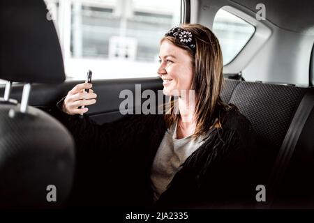 Ein Taxi oder ein Uber-Passagier, der über das Telefon auf dem Rücksitz des Autos spricht Stockfoto