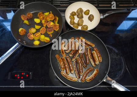 Nürnberger Würstchen, Bratkartoffeln in Pfannen auf dem Herd, Bayern, Deutschland Stockfoto