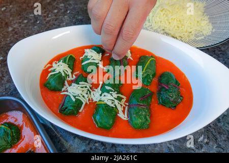 Schwäbische Küche, Bietigheimer Laubfrösche in Paprikasoße, Sauce, gefüllte Mangold Blätter in Paprikasoße werden mit Käse bestreut, geriebt Stockfoto