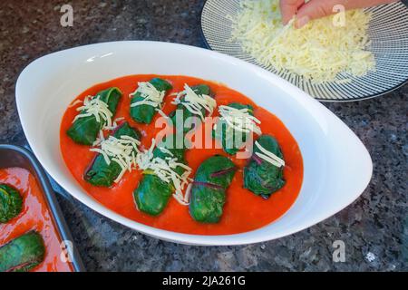 Schwäbische Küche, Bietigheimer Laubfrösche in Paprikasoße, Sauce, gefüllte Mangold Blätter in Paprikasoße werden mit Käse bestreut, geriebt Stockfoto