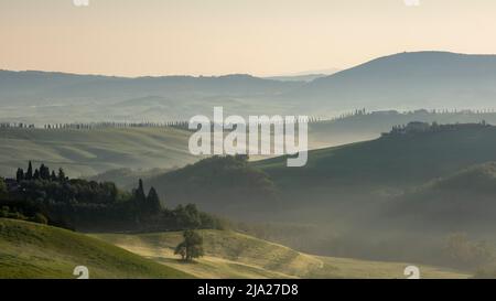 Sonnenaufgang mit Nebel in hügeliger Landschaft, Crete Senesi, Provinz Siena, Toskana, Italien Stockfoto