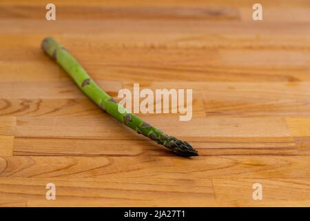 Ein einzelner Speer aus grünem Spargel auf einem Holzhintergrund Stockfoto