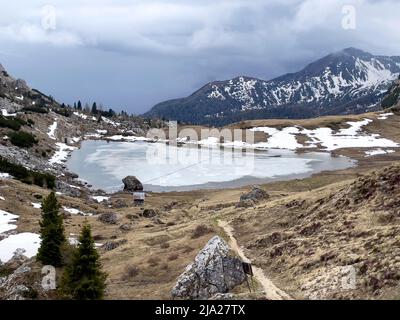 Bergsee Lago di Valparola mit auftauender Eisoberfläche, Passo di Valparola, Dolomiten, Provinz Belluno, Venetien, Italien Stockfoto