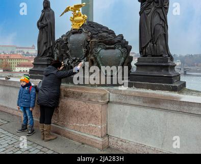 Betende Frau mit Kind auf der Karlsbrücke, Prag, Tschechische Republik Stockfoto